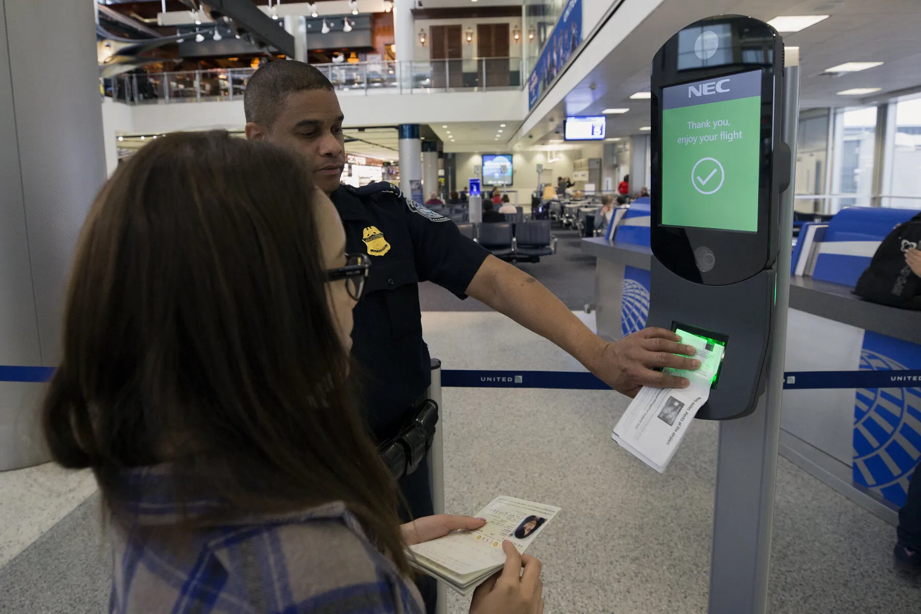 A border officer assists a passenger at a biometric airport screening station