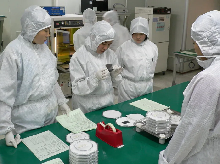 People in cleanroom suits inspecting an optical circuit